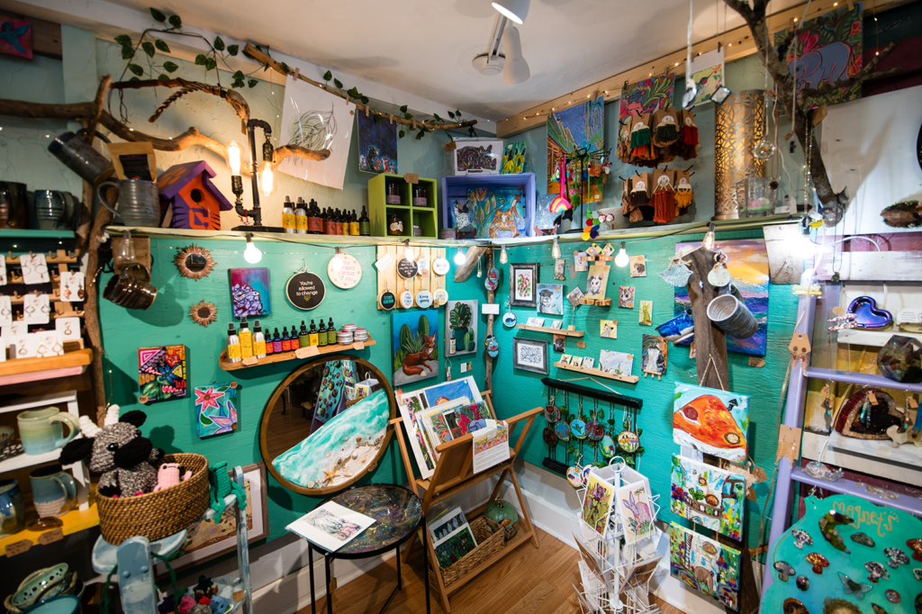 Colorful craft shop interior with artworks, ceramics, and handmade items on turquoise walls and shelves.
