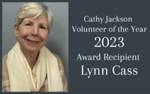 Featured Image Lynn Cass → Discover Saluda, NC Portrait of an older woman smiling on the left; on the right, a dark teal panel reads 'Volunteer of the Year 2023' with 'Award Recipient' text (no names shown).
