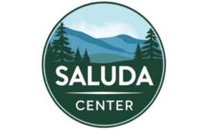 Circular logo for Saluda Center featuring a forest and mountain landscape in blue and green tones with the word SALUDA CENTER in white.