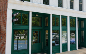 Entrance to Saluda City Hall with green windowed doors and brick facade.