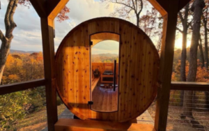 RechargeFeaturewebp Circular wooden door of a treehouse, opening to a sunlit balcony with autumn trees and distant hills.