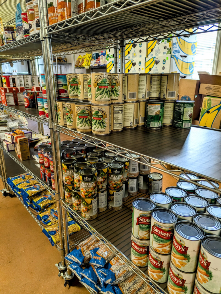 Shelf stocked with canned vegetables and boxed foods in a grocery store.